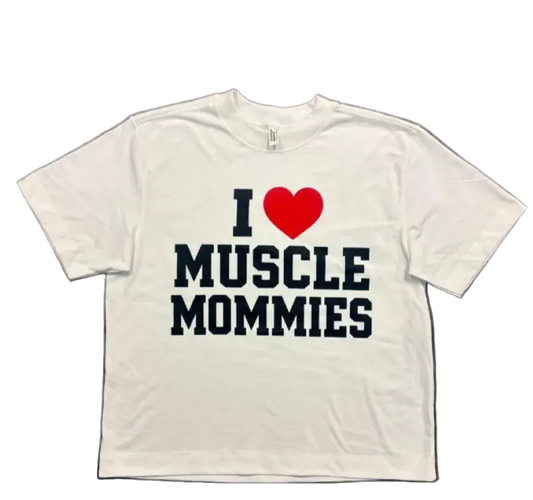 A white short-sleeve t-shirt laid flat on a dark textured surface, featuring a graphic print that reads 'I' followed by a red heart and 'MUSCLE Mommies' in dark navy lettering.